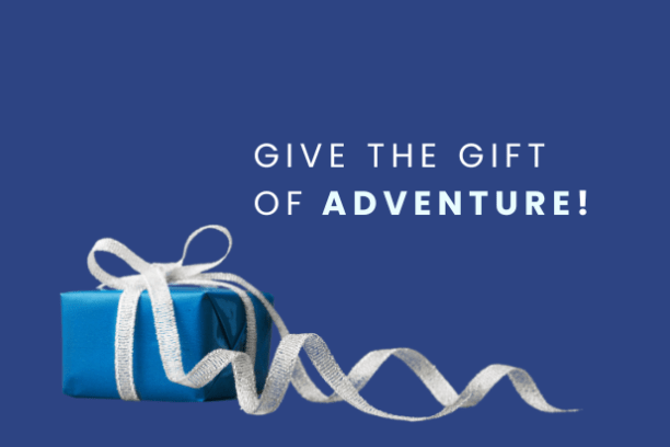 Blue gift box with white ribbon on blue background with 'Give the Gift of Adventure!' text.